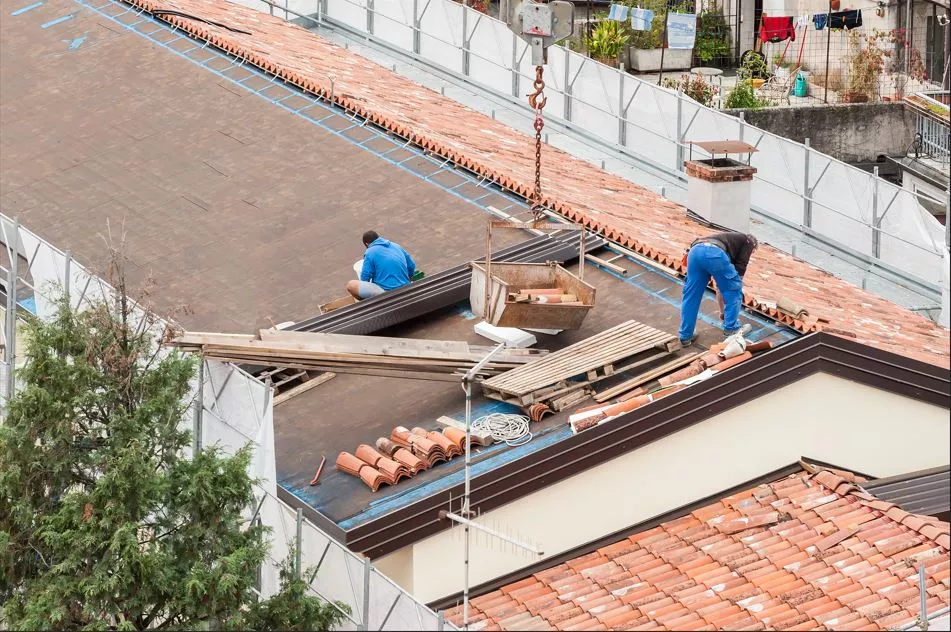 Professional roofing team removing old materials and prepping a Columbus rooftop for a new terracotta tile installation.service