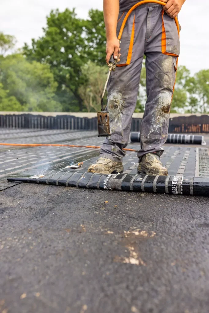 A specialized roofing technician using a torch to apply heat-activated waterproofing membrane to a flat roof in Scottsdale.