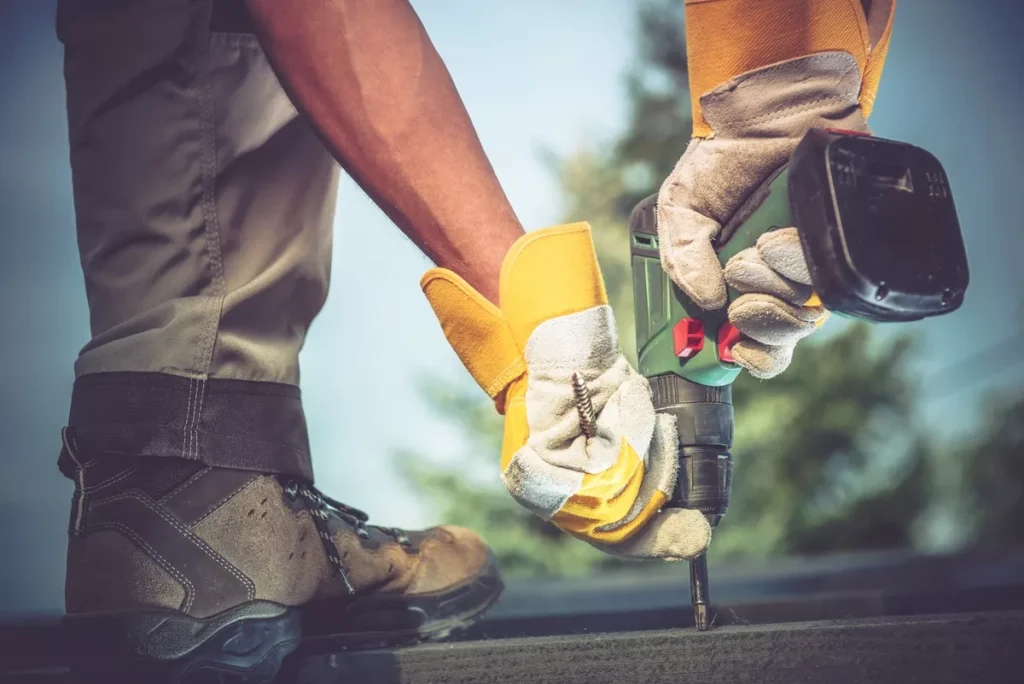 A roofer using a cordless drill to securely fasten roofing components during a professional installation in Scottsdale.